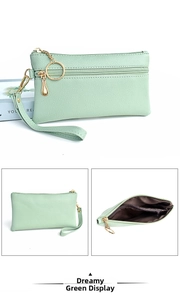 Detail view of double zippers and lychee grain texture on a pastel green wristlet bag
