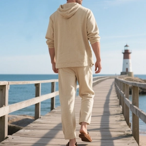 Rear view of loose beige linen hooded shirt and matching pants on a scenic wooden path