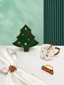 Festive table setting with Christmas tree plate, holiday mug, and metal napkin rings