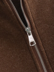 Detailed macro view of silver metal zipper and textured brown fabric on sports jacket