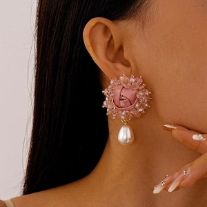 Close-up of pink fabric rose earrings with crystal beads and a teardrop pearl pendant
