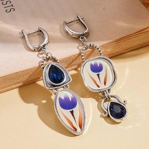 Gros plan de boucles d'oreilles vintage asymétriques avec pierres bleues et émail