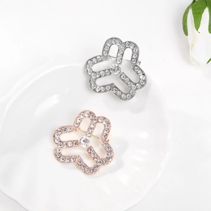 Elegant floral brooches in silver and rose gold with pavé crystals on a white plate