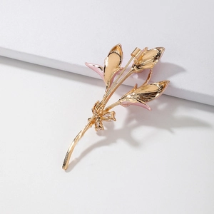 Spilla vintage a fiore dorata con smalto rosa e zirconi su uno sfondo bianco