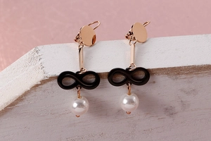 Detail of rose gold infinity drop earrings with black charm and elegant white pearl pendant