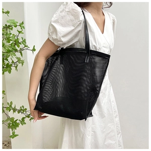 Detail view of black mesh tote bag with PU leather handles and breathable grid texture