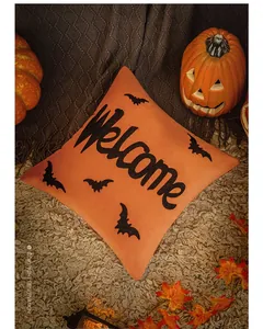 Close-up of orange Halloween pillow cover featuring black Welcome text and bats