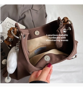 Dettaglio interno della borsa tote marrone con chiusura magnetica e charm in peluche