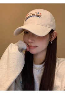 Detail of beige cotton baseball cap with Don't be late embroidery on a fashion model