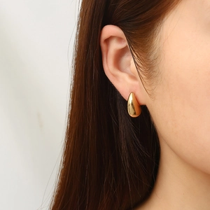 Elegant gold teardrop earrings for women made of polished stainless steel shown on model