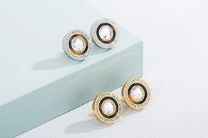 Macro detail of gold and silver hoop earrings with clear zircon and dark enamel inlay