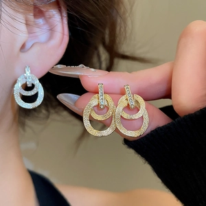 Dettaglio macro di orecchini a cerchio intrecciati placcati oro 18k con pavé di cristalli