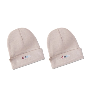 Two beige knitted beanies with colorful dream embroidery and stars on a white background
