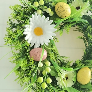 Close-up of Easter wreath with white daisies, pastel spotted eggs and lush green foliage
