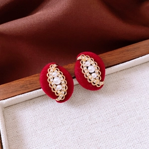 Macro shot of red velvet oval earrings with gold frames and inlaid pearls