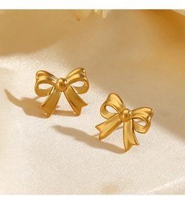 Macro view of 18K gold-plated stainless steel bow earrings on beige satin fabric