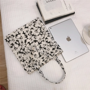 Close-up of black and white floral canvas tote bag with textured waffle background