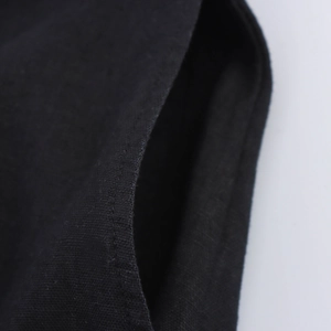 Détail de la poche latérale et de la texture en lin naturel sur une robe licou noire