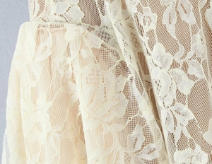 Macro shot of apricot lace fabric featuring intricate floral hollow-out textures and mesh