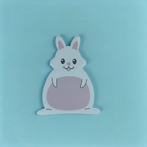Close-up of a cute white and pink bunny-shaped sticky note on a blue background