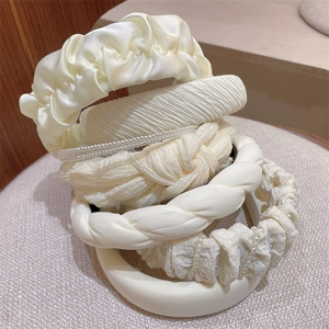 Detailed set of creamy white fabric headbands featuring pearls and pleated textures