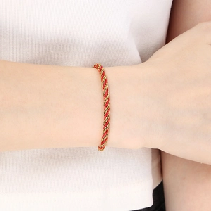 Close-up of red and gold woven spiral bracelet worn on a wrist for a stylish look