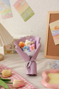 Detailed view of handmade knitted flower bouquet in purple wrapping with ribbon