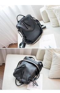 Detail of black pebbled leather backpack with tassel zippers and metal rivet accents