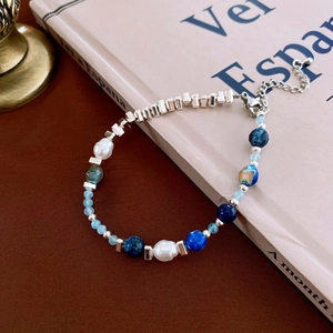 Detailed shot of freshwater pearls and blue gemstone beads on a vintage book