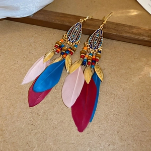 Detail of bohemian drop earrings with colorful beads and natural pink and blue feathers