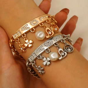 Detail of layered gold and silver bracelet with LOVE rhinestones and heart charms