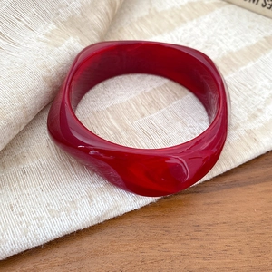 Bracciale geometrico in acrilico rosso scuro con trama a onde in resina traslucida