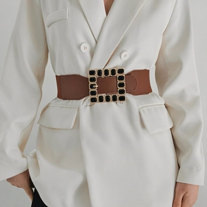 Detail of brown elastic waist belt with large gold square buckle and black gemstones