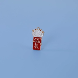 Détail d'un pendentif Maneki-neko rouge avec accents dorés et parchemin porte-bonheur DIY