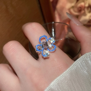 Dettaglio anello quadrifoglio con smalto blu e gemma viola sulla mano