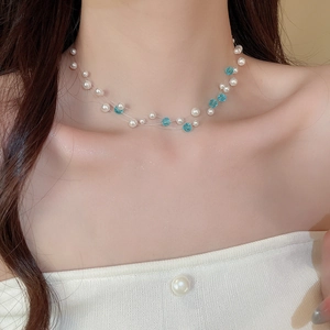 Detail of double-layer beaded necklace featuring blue crystals and white pearls on neck