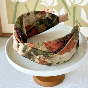 Close-up of printed tie-dye wide headband with knot design on a white pedestal