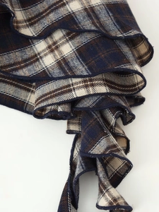Detailed view of plaid ruffle trim and soft flannel fabric on a blue checkered top