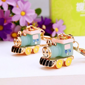 Macro shot of mint green cartoon train keychain with blue rhinestones and star-shaped wheels