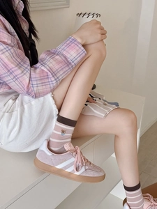 Détail de chaussettes en résille rose avec broderie ours et baskets Gazelle