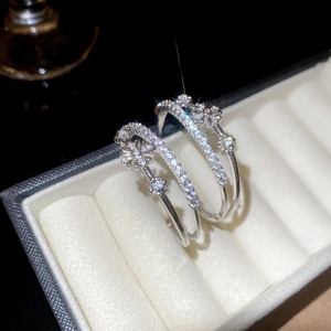 Détail macro de boucles d'oreilles fleurs en C avec zircons dans un écrin à bijoux blanc