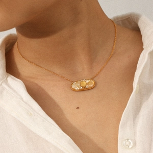 Detail of gold shell pendant with embossed texture on stainless steel chain for women
