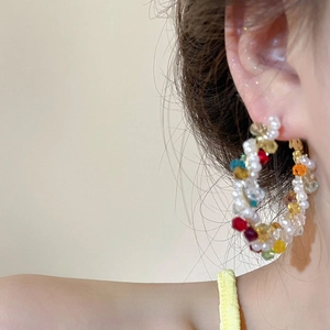 Close-up of colorful beaded hoop earring with pearls and crystals on a model's ear