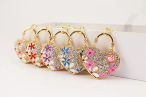 Detailed macro view of heart-shaped keychains with crystal rhinestones and enamel flowers