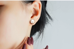 Close-up of elegant white pearl stud earring on model showcasing its natural luster