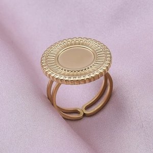 Macro detail of golden stainless steel ring with sunburst pattern on a silk background