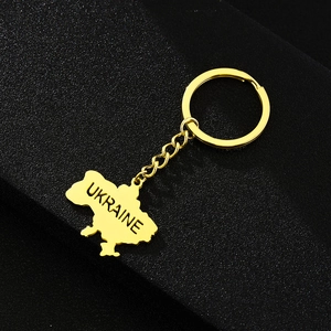 Detail of a golden Ukraine map pendant keychain with UKRAINE engraving on dark background