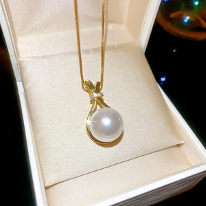 Detailansicht einer glänzenden Perlenkette mit goldenem Anhänger auf Samt-Geschenkbox