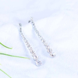 Sparkling long tassel earrings with silver base and clear zircons on soft background