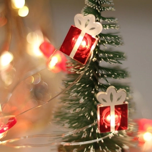 Close-up of red gift box LED lights on a mini Christmas tree with warm bokeh background